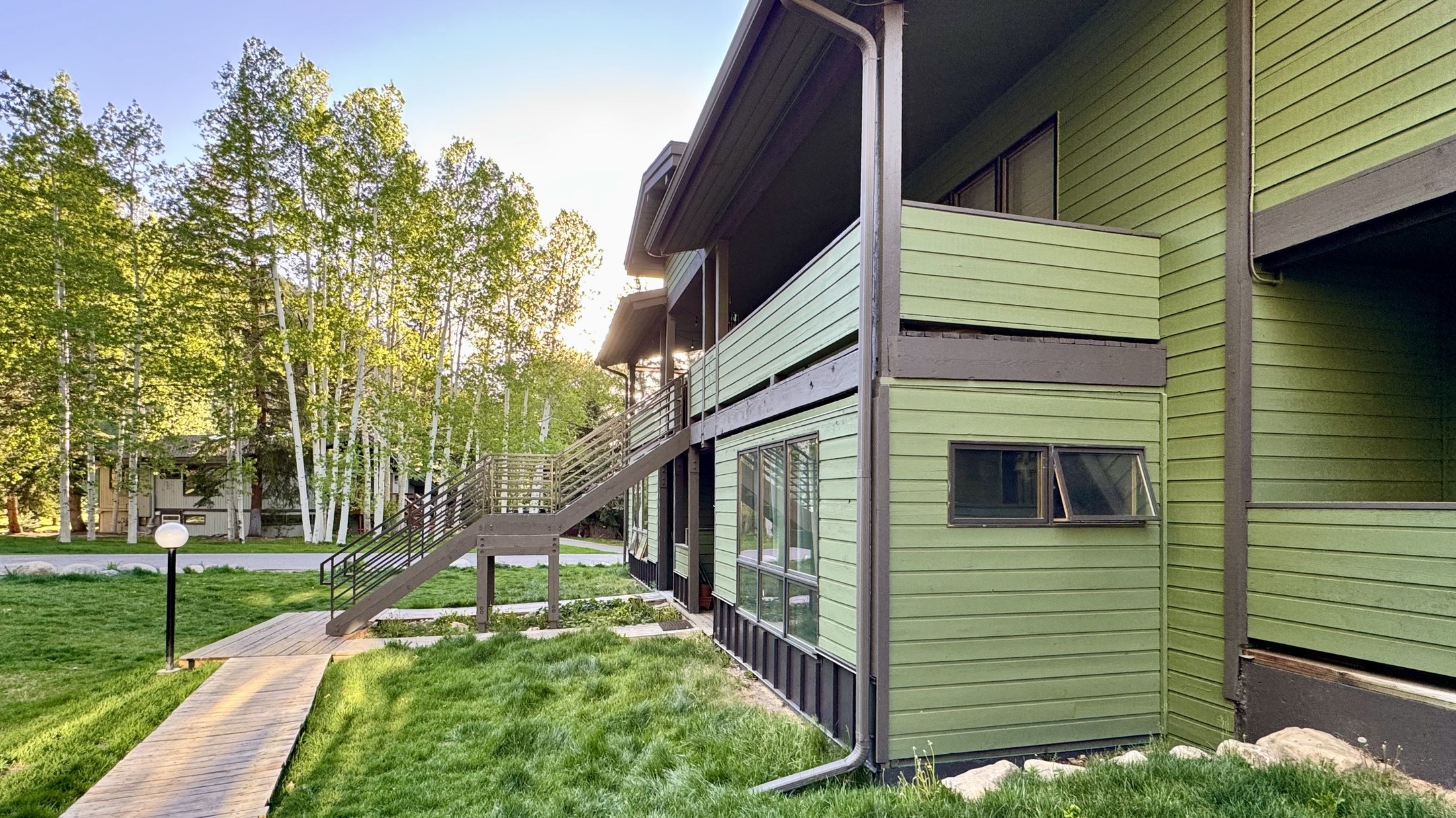 View along the building's side. Walkway access connects the unit's grassy outlook to Cottonwood Rd.